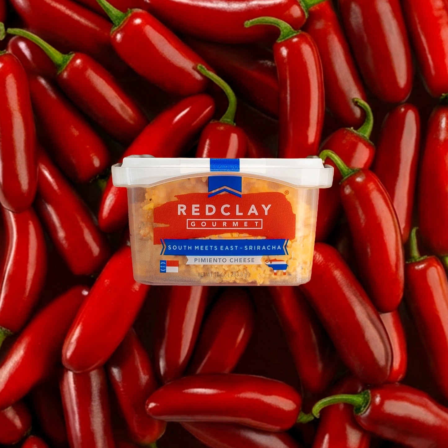 Red Clay Gourmet's South Meets East ~ Sriracha flavored Pimiento Cheese container surrounded by red peppers
