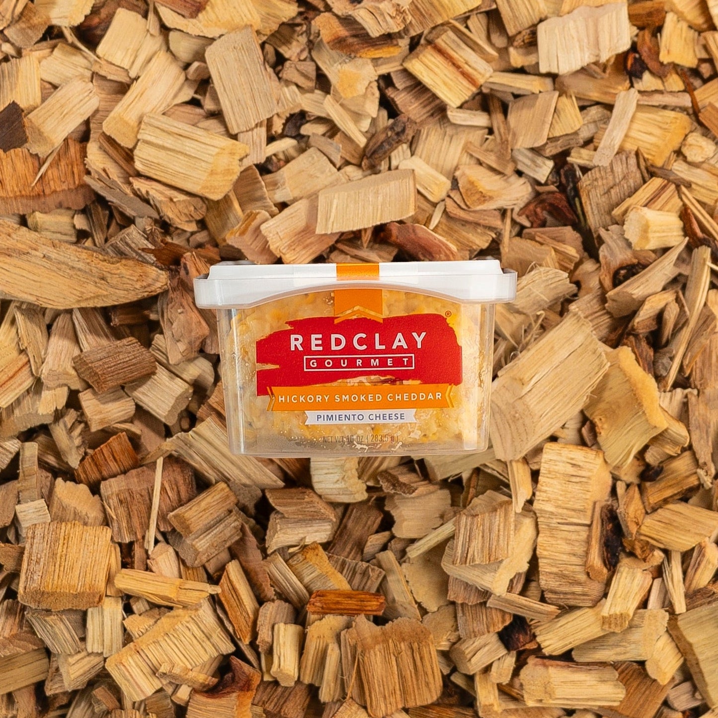 Red Clay Gourmet's Hickory Smoked Cheddar flavored Pimiento Cheese surrounded by hickory wood