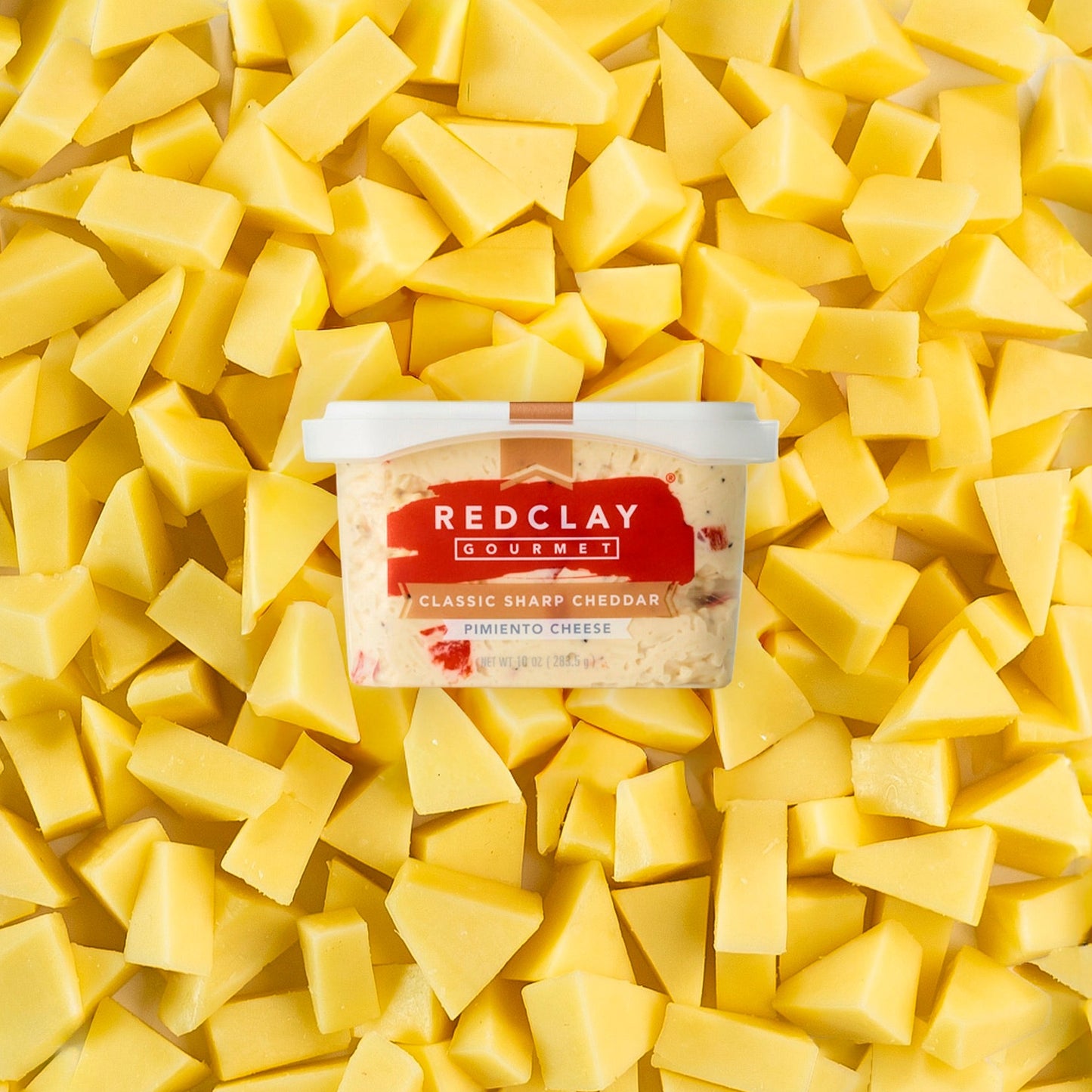 Red Clay Gourmet's Classic Sharp Cheddar Pimiento Cheese tub surrounded but sliced sharp cheddar cheese
