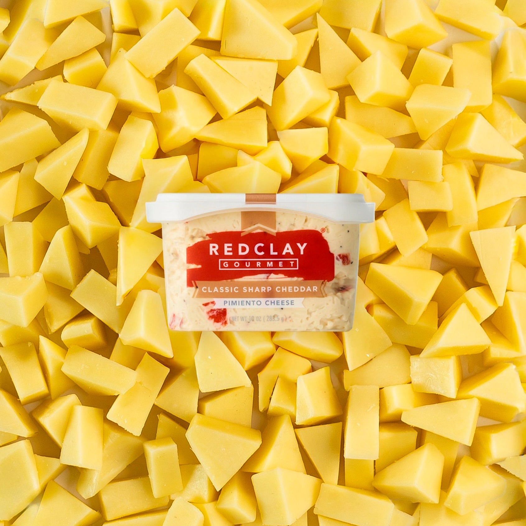 Red Clay Gourmet's Classic Sharp Cheddar Pimiento Cheese tub surrounded but sliced sharp cheddar cheese
