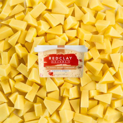 Red Clay Gourmet's Classic Sharp Cheddar Pimiento Cheese tub surrounded but sliced sharp cheddar cheese